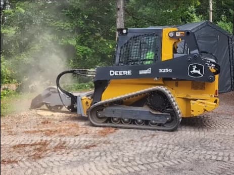 John Deere 325G compact track loader grinding a stump